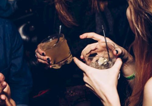 People enjoying a night out, holding drinks and laughing with friends, creating a lively and social atmosphere.