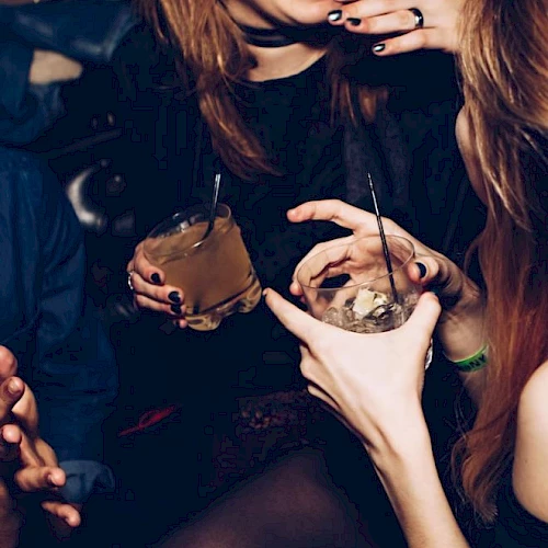 People enjoying a night out, holding drinks and laughing with friends, creating a lively and social atmosphere.