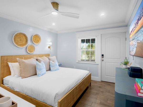 A cozy bedroom with a bed, decorative baskets on the wall, TV, books, and a window letting in natural light, creating a serene ambiance.