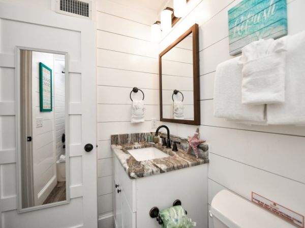Bathroom with a vanity, mirror, towels, starfish decor, and a door with a full-length mirror. The style is modern and clean.