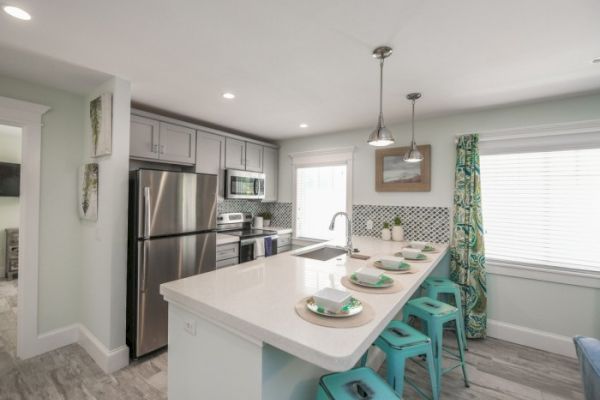 A modern kitchen with stainless steel appliances, an island with bar stools, and colorful decor.