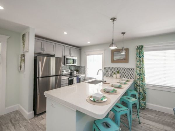 A modern kitchen with stainless steel appliances, an island with bar stools, and colorful decor.