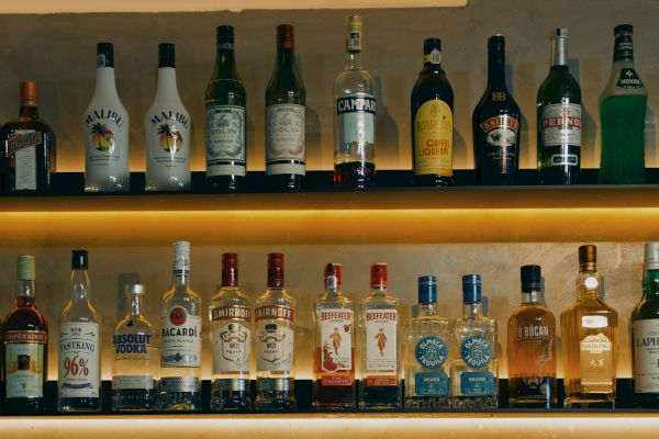 A selection of various liquor bottles displayed on two shelves, including brands like Cointreau, Malibu, Campari, Baileys, and Absolut Vodka.