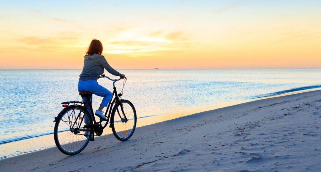 person biking on beach in sunset